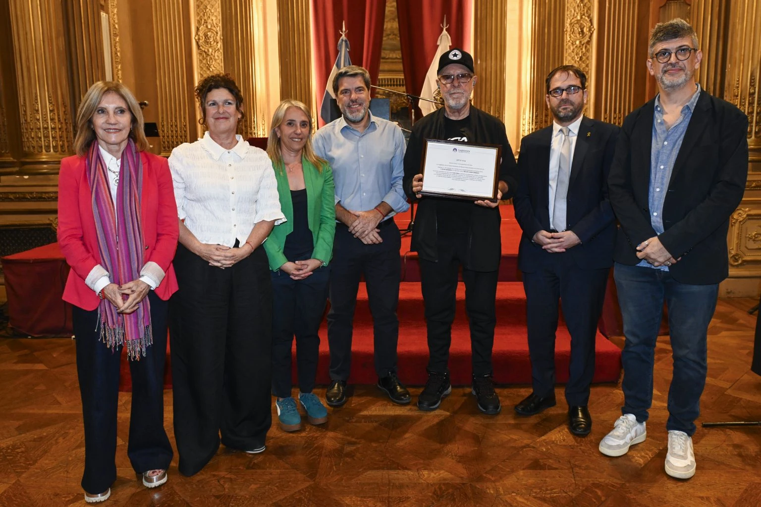 María Luisa González Estevarena, integrante de la Comisión de Cultura de la Legislatura porteña; Gabriela Ricardes, ministra de Cultura de la ciudad, la Legisladora porteña Cecilia Ferrero; Matías López, vicepresidente primero de la Legislatura de la ciudad; el cantautor León Gieco, el presidente de AMIA, Amos Linetzky, y Elio Kapszuk, director de Arte y Producción de la institución.