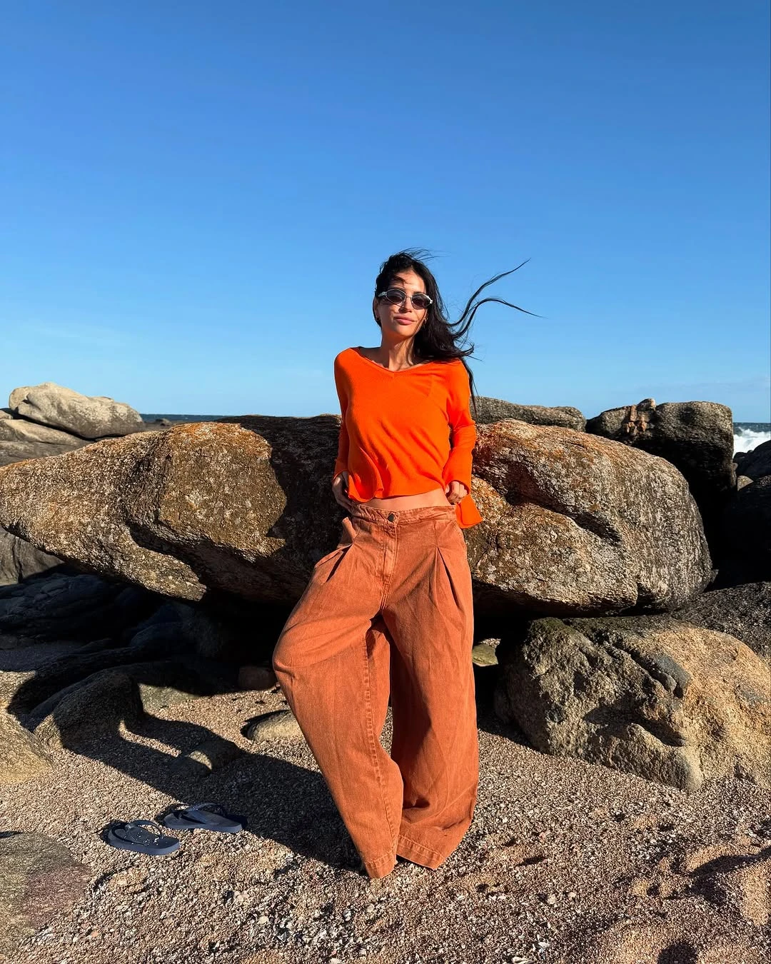 pantalón de gabardina con tablas frontales y de piernas anchas y un swetter de calce irregular con ruedo ancho y tajos laterales de color naranja. 